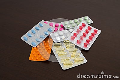 Heap of packs of pills and capsules isolated on brown wooden background Stock Photo