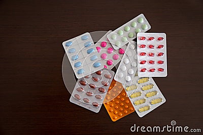 Heap of packs of pills and capsules isolated on brown wooden background Stock Photo