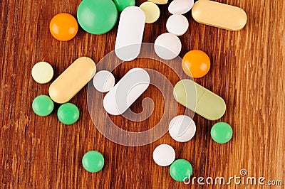 Heap of pills on wooden desk Stock Photo