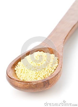 Heap of raw, uncooked couscous in wooden spoon over white Stock Photo