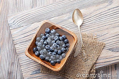 Heap ripe sweet blueberries and spoon on wooden table top view Stock Photo