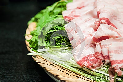 Heap of rolled pieces raw sliced bacon on green mizuna lettuce i Stock Photo