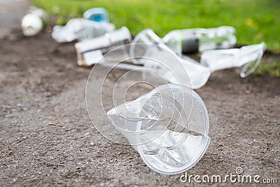 Heap of rubbish on the path, closeup. Empty used plastic cups and plastic bottles Stock Photo