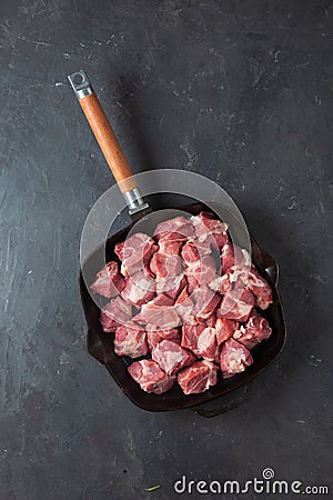 Heap small pieces raw meat in frying pan Stock Photo