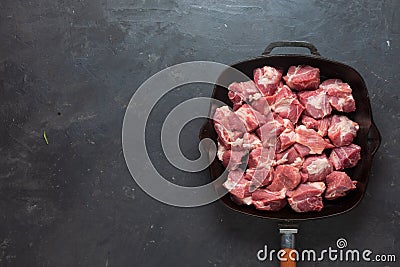 Heap small pieces raw meat in frying pan Stock Photo