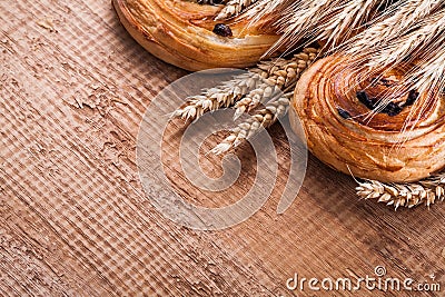 Heap of wheat ears sweet raisin pastry on oaken Stock Photo