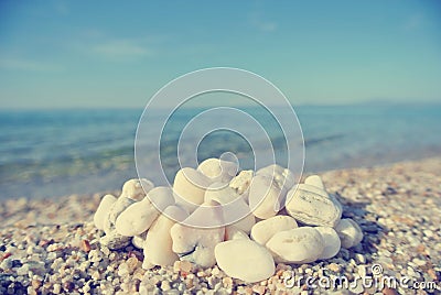 Heap of white pebbles on pebbly beach; faded, retro style Stock Photo