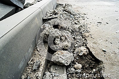 Heaps of demolished asphalt lying on the sidewalk near the pit for installing a curb. Broken asphalt. A hole in the road surface. Stock Photo