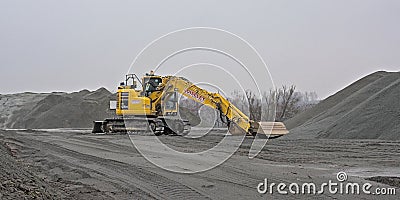 Yellow crane and gravel heaps and industrial buildings in a stone quarry Editorial Stock Photo