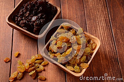 Heaps of yellow and dark Raisins, in a wooden bowls. Stock Photo