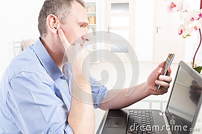 Hearing impaired man working with laptop and mobile phone Stock Photo