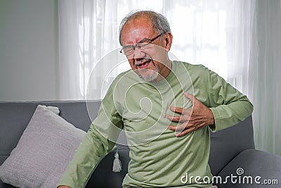 Heart attack symptoms, Senior heart attack suffering indoor Stock Photo