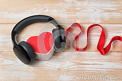 Heart box with stereo headphones and red ribbon. Music of the heart concept. Wooden background Stock Photo