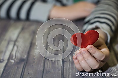 Heart in child hands. Wooden background. A child holds a heart in his hands. Valentines Day. Stock Photo