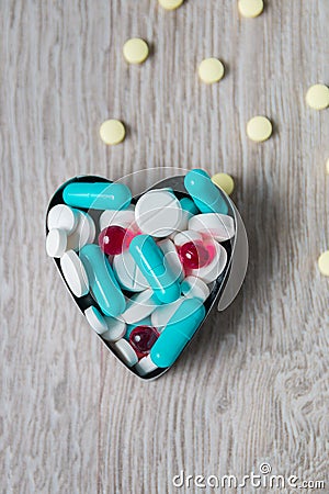 Heart from colorful medication and pills above on grey wooden background. Copy space. Top view, frame. Painkillers, tablets, gene Stock Photo