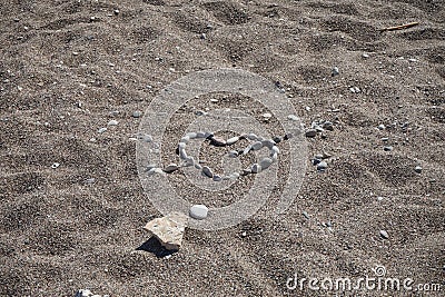 Heart with Cupid`s arrow is made of stones on the beach. Kolimpia, Rhodes, Greece Stock Photo