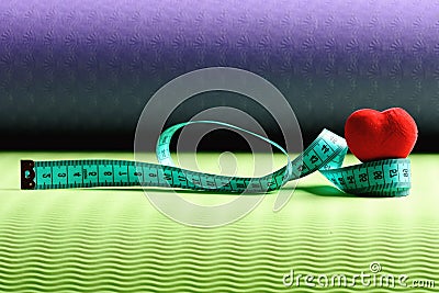 Heart decoration and flexible ruler lying on yoga mat Stock Photo