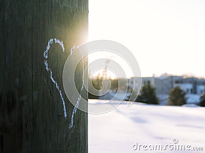 Heart drawn with white chalk on electric pole with sun shining and snow Stock Photo