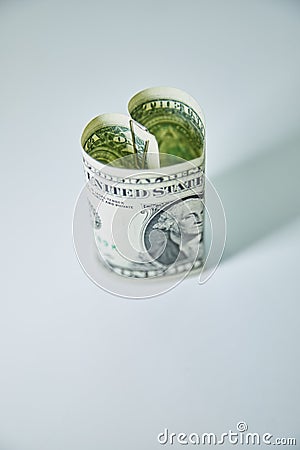 Heart folded from one dollar bill over gray background with copy space. Concept image of money love Stock Photo