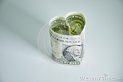 Heart folded from one dollar bill over gray background with copy space. Concept image of money love Stock Photo