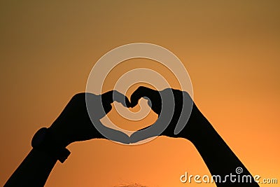 Heart made hands forming heart shape with gold sunset silhouette, Shadow of woman hand love signs in happy playing feel evening Stock Photo