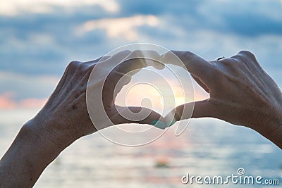 Heart made by hands with sun inside on the beach Stock Photo