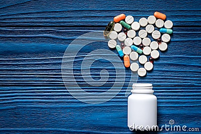 Heart made of pills and pill bottle on blue wooden table background top view copyspace Stock Photo