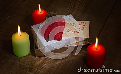 A heart made of red thread, gift boxes, a pine cone and a piece of paper with the words `My beloved` and a hand-drawn face for Val Stock Photo