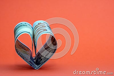 Heart from one hundred dollar bills USA on a red background. Concept of money, love and a gift for Valentine`s Day. Copy space Stock Photo