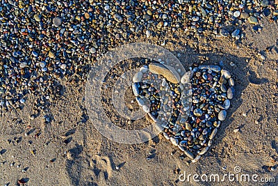 Heart of pebbles on the golden and soft sand on the beach Stock Photo