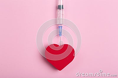 Heart on a pink background with a medical syringe. Heart health and love and medicine concept Stock Photo