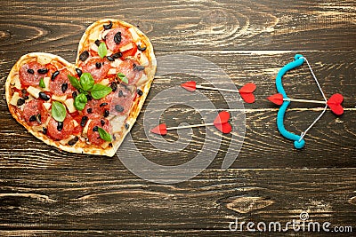 Heart pizza love concept Valentines day romantic dinner Italian pastry with cupid onions. on a wooden table. Flat-lay Stock Photo