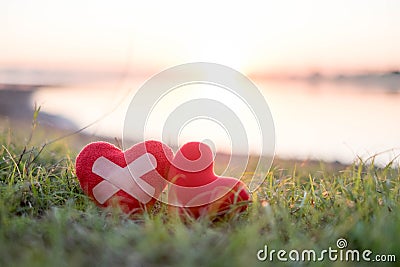 Heart with plaster and red heart in the background, the sun falls Stock Photo