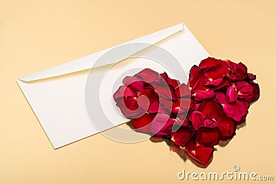 Heart of red petals lying on top of an open blank envelopes Stock Photo