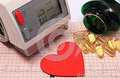 Heart shape, blood pressure monitor and tablets on electrocardiogram Stock Photo