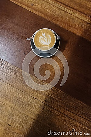 Heart shape foam drawed on hot fresh coffee latte art on wooden table at vintage cafe Stock Photo