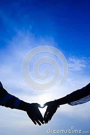 Heart shape of hands against sea during sunset Stock Photo