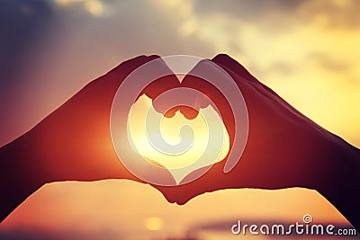 Heart shape making of hands against bright sea sunset Stock Photo