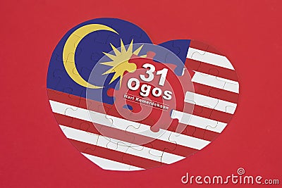 Heart shape Malaysia Flag jigsaw puzzle with a written word 31 Ogos Stock Photo