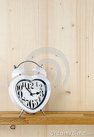 A heart shaped alarm clock on a shelf Stock Photo