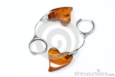 Heart-shaped amber earrings on a silver chain with round earwires handcuffs. On a white background, top view. Stock Photo