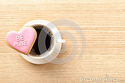 Heart shaped cookie with written phrase Be Mine and cup of coffee on wooden background, top view Stock Photo