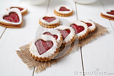 Heart shaped cookies with jam, delicious homemade holiday surprise sweet on white wooden background for Valentines day Stock Photo