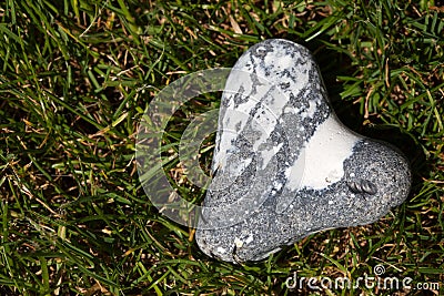 Heart shaped flintstone lying in the grass with copy space Stock Photo