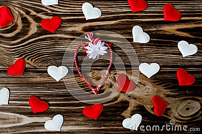 Heart-shaped martisor or martenitsa surrounded by hearts on wooden background Stock Photo