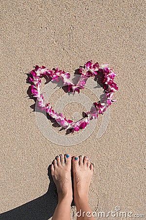 Heart shaped orchid flower garland white sea sand beach with woman feet Stock Photo