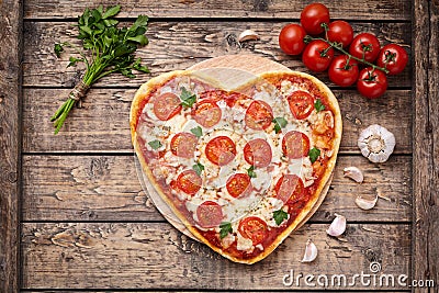 Heart shaped pizza margherita romantic love food concept with mozzarella, tomatoes, parsley, and garlic composition on Stock Photo