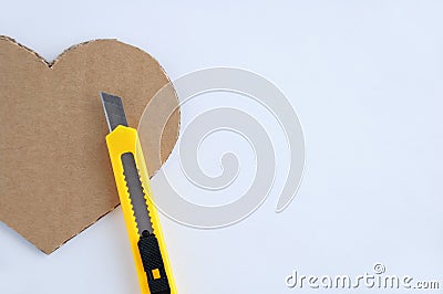 Heart symbol made of brown cardboard with jagged edges and a clerical knife Stock Photo