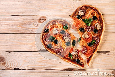 Heartbreak shaped pizza with tomatoes and mozzarella for Valentines Day on vintage black background. Food concept of Stock Photo