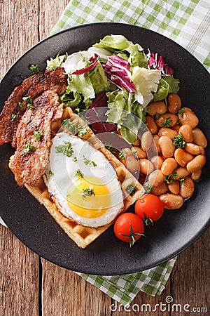 Hearty breakfast with fried egg, waffles, bacon, mix salad and b Stock Photo